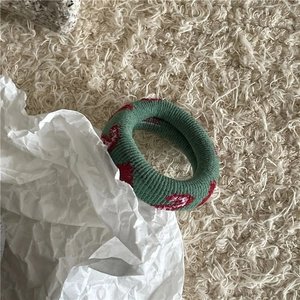 Détail d'un chouchou en maille verte avec motifs de cœurs rouges pour cheveux