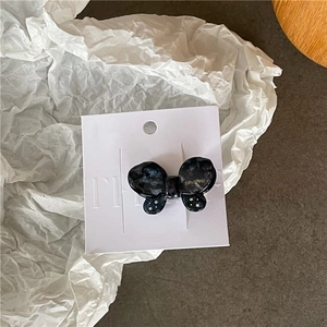 Detail of a dark marble pattern acetate butterfly hair clip on white display card