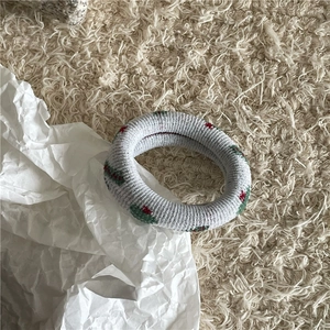 Gros plan sur chouchou en maille grise avec motif floral rouge et vert tissé