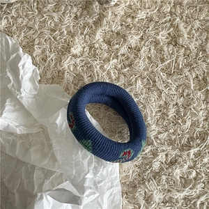 Gros plan d'un chouchou en maille avec jacquard de cerises colorées sur tissu bleu