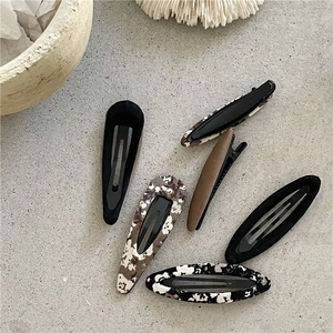 Détail de six barrettes à motifs floraux et couleurs unies sur surface texturée