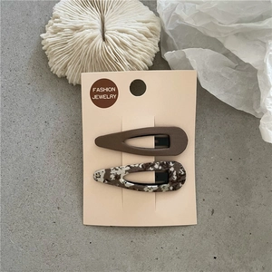 Détail de pinces à cheveux BB en tissu floral et marron sur carte de présentation