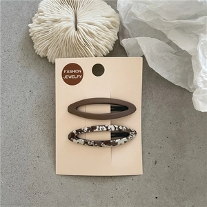 Détail de barrettes BB à fleurs et marron uni sur une carte de présentation bijoux
