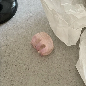 Detail of pink marble acetate hair claw clip with interlocking teeth on textured surface
