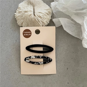 Lot de barrettes ovales en tissu noir et à fleurs sur une carte de présentation
