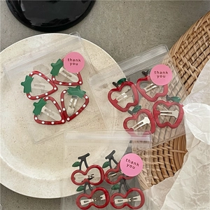 Close-up of cute fruit-shaped hair clips including strawberry, apple and cherry designs