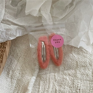 Detail of soft cream peach faux fur hair clips in a gift package with thank you sticker