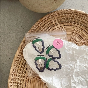 Set of four glossy purple grape fruit hair clips with green leaves in a gift bag