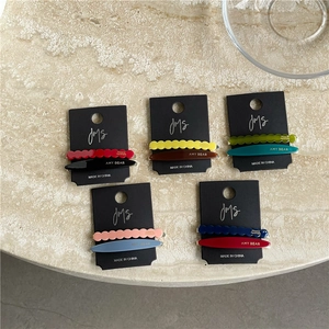 Five sets of geometric acetate hair clips in various colors on a black display card