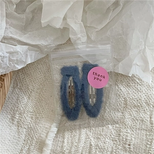 Detail of dark blue plush BB hair clips in transparent packaging with thank you sticker