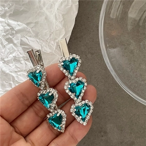 Detail of three blue heart-shaped crystal hair clips with silver-tone rhinestone borders
