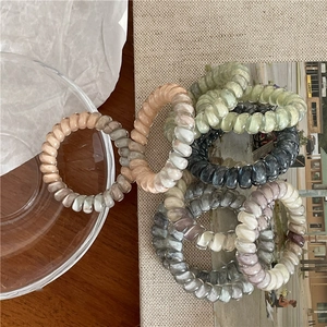 Colorful gradient spiral hair ties with marble texture on wooden surface display