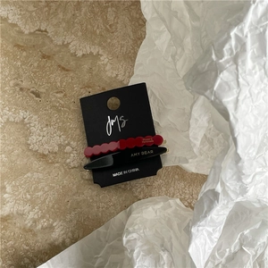 Detail of red wavy and black sleek acetate hair clips on branded display card
