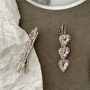 Detail of two silver hair clips with pink heart rhinestones and fine white diamonds