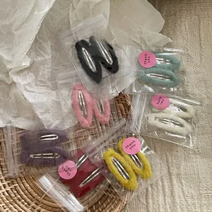 Detailed view of colorful fabric-covered teardrop hair clips set in transparent packaging