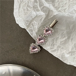Close-up of three pink heart-shaped gems with rhinestone edges on a silver duckbill clip