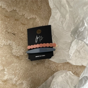 Detail of pink wavy and blue acetate hair clips with AMY BEAR logo on a black card