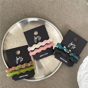 Macro view of three pairs of wave-shaped acetate hair clips on black display cards