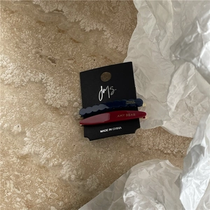 Close-up of geometric acetate hair clips in navy blue and burgundy on a JMS card