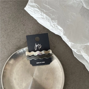 Detailed view of wavy acetate hair clips with marble texture on a luxury metal tray