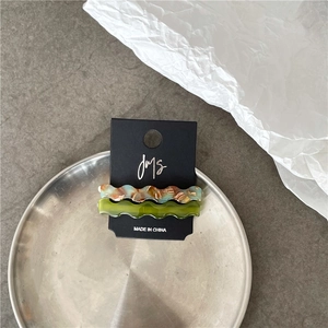 Close-up of wavy acetate hair clips with marble texture on black display card