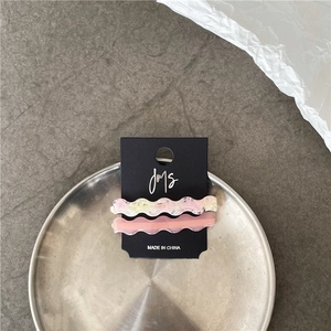 Macro view of wave-shaped marble texture and pink acetate hair clips on a card