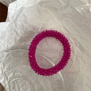 Detail van de glinsterende roze kristallen kralen op de elastische haarband met facetten