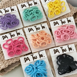 Macro shot of colorful elastic towel hair ties in cream tones with branded card packaging