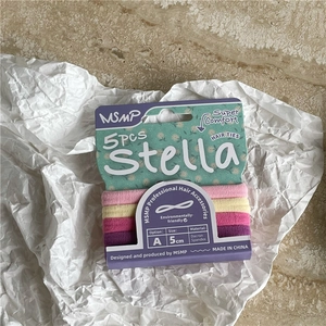 Detailed view of five 5cm gradient cream hair ties on marble background with packaging