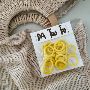 Detail of yellow elastic towel hair ties set in a transparent pouch on a beige background