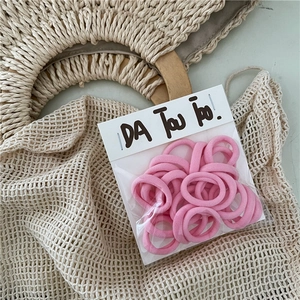 Detailed view of pink seamless hair ties in transparent retail packaging with hanging card