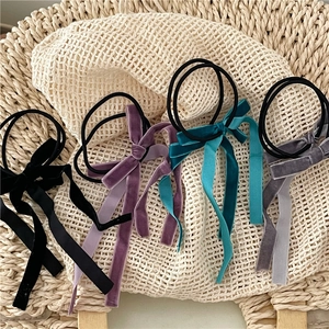 Detail of colorful velvet long ribbon bow scrunchies on elegant woven textures