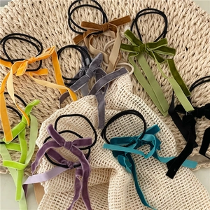 Set of colorful velvet bow hair ties with long ribbons on a textured woven mat background
