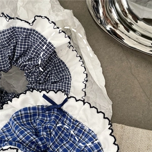 Close-up of blue plaid fabric scrunchies with white ruffle edges and delicate bow details