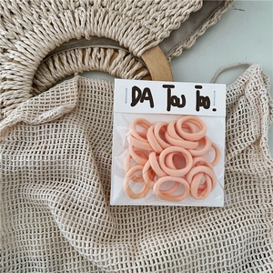 Detail of pink high-elastic hair bands in independent branded packaging on soft fabric