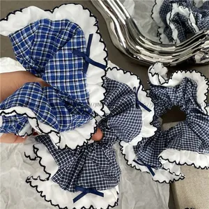 Macro view of blue plaid hair scrunchie with white ruffled lace and ribbon bow