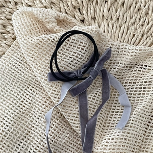 Detailed close-up of grey velvet bow hair tie with long ribbons on knit fabric