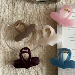 Set of five colorful heart-shaped jelly texture hair claws on a cozy beige plush background