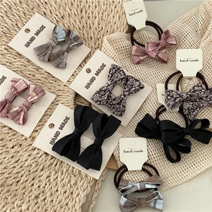 Flat lay of handmade plaid and floral bow hair ties and clips on a woven mat display