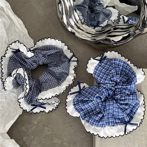 Blue plaid fabric scrunchie with white lace trim and dark blue ribbon bow for women