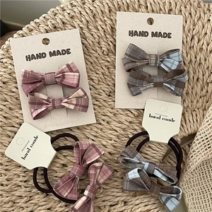 Detail of plaid bow hair clips and ties set on a textured straw background