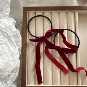 Detail of red velvet bow hair ties set with long ribbons on a jewelry display tray