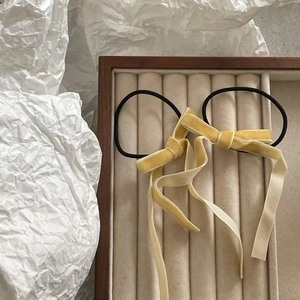 Detailed view of yellow velvet bow hair ties with long ribbons on a velvet jewelry tray