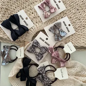 Colorful plaid and floral bow hair accessories set including hair ties and clips on a mat