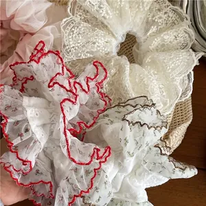 Lot de chouchous géants en dentelle et tulle avec broderies florales sur table bois