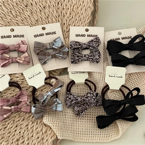 Detail view of plaid and floral bow hair ties and clips on woven texture background