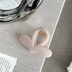 Macro view of jelly texture pink heart hair claw clip with golden metal spring detail