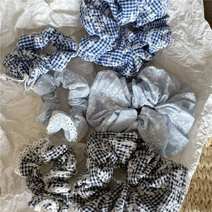 Close-up of fabric hair scrunchies with plaid patterns, lace edges and floral embroidery