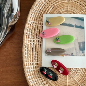 Lot de 6 barrettes cerise en strass de couleurs variées sur un plateau tressé