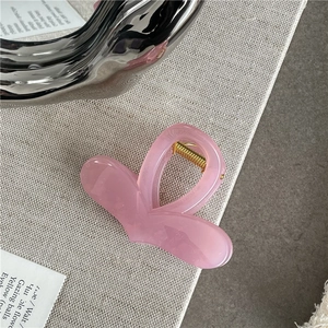 Close-up of pink heart hair claw clip with jelly texture and golden metal spring